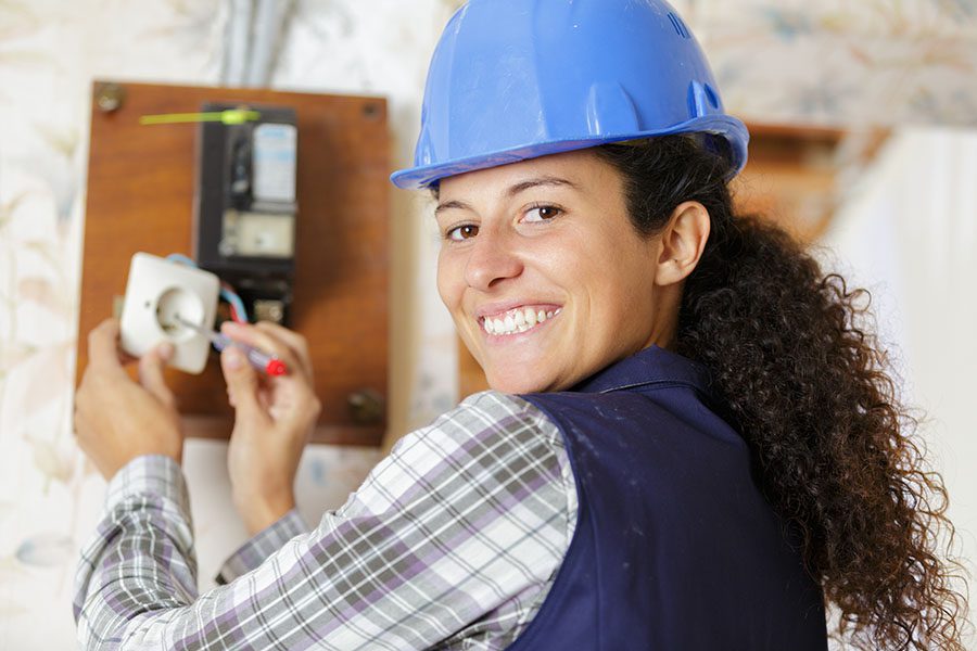 Contact - Closeup View of Smiling Female Electrician Working on Fixing an Electrical Socket Problem